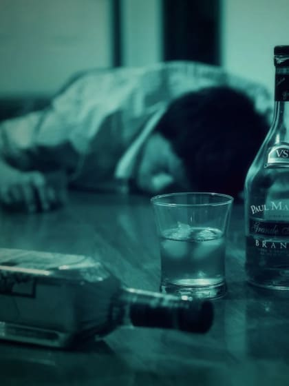 Пьяный мужчина, лежащий на полу среди бутылок