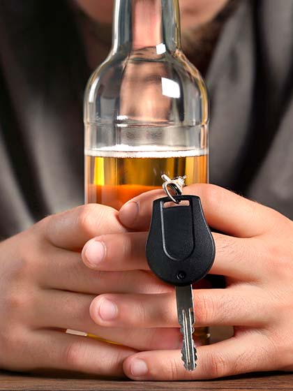 мужчина держит в руках бутылку пива и ключи от машины