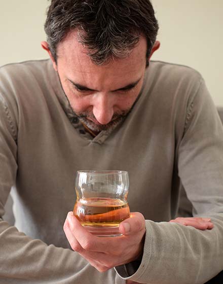 грустный мужчина держит в руках стакан с алкоголем